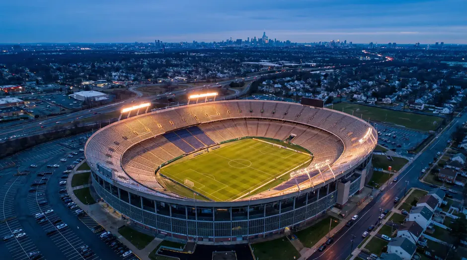 Luftaufnahme des MetLife Stadium in New Jersey bei Abenddämmerung mit beleuchtetem Spielfeld und gefüllten Rängen