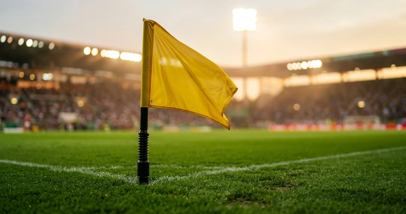 Grüner Rasen eines Fussballstadions mit Eckfahne und Flutlicht in der Abenddämmerung