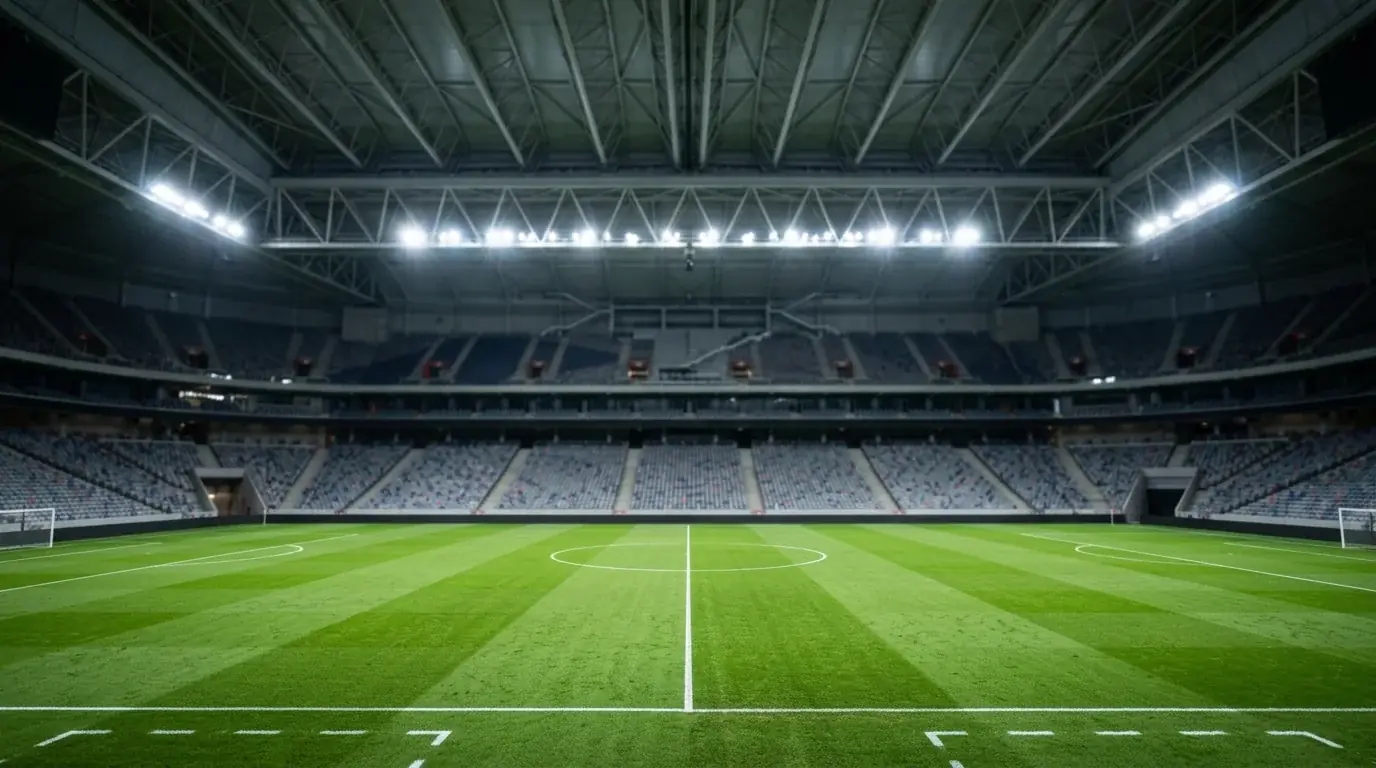 Stadion mit geschlossenem Dach und Rasen im Flutlicht, rote Farbakzente auf den Rängen