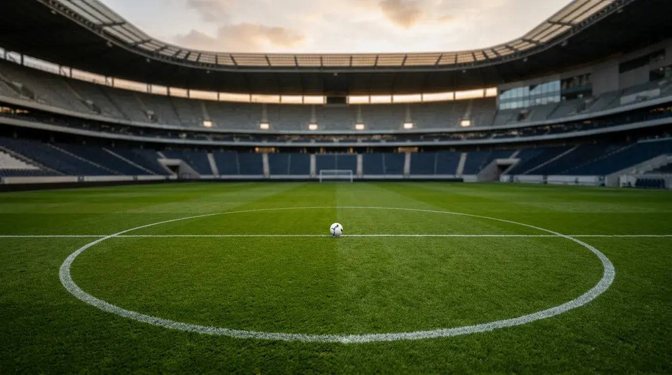 Rasen eines WM-Stadions mit Anstosskreis im Abendlicht, leere Tribünen im Hintergrund